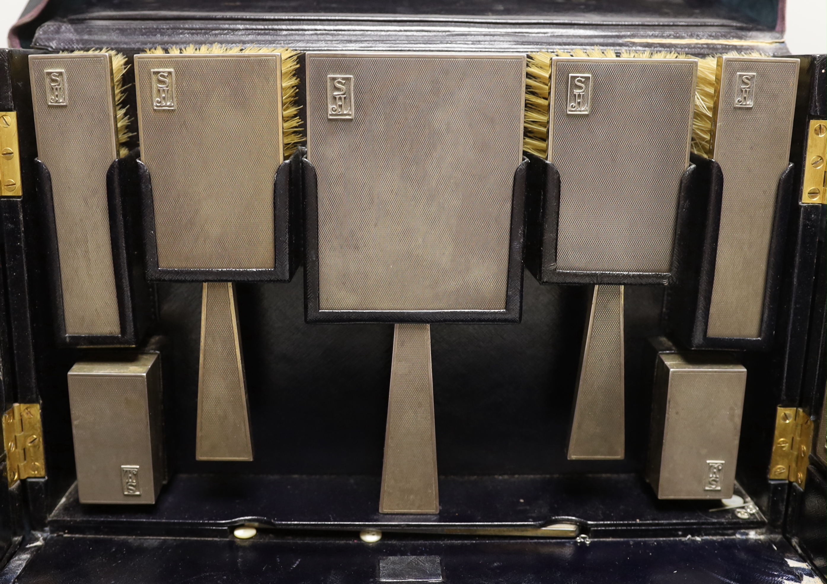 A George VI leather travelling vanity case, containing seventeen monogrammed silver mounted items, including ten mounted glass toilet jars, two boxes, four brushes and a hand mirror, Asprey & Co, London, 1936, case width